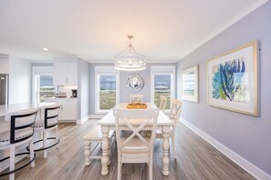 Une cuisine moderne avec des meubles blancs, une table à manger avec des chaises et un lustre.