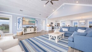 A spacious living area with a large sofa, a coffee table, and a view of the ocean. - Blue Hideaway 2888 3 Bedroom Home (Gulf Shores)