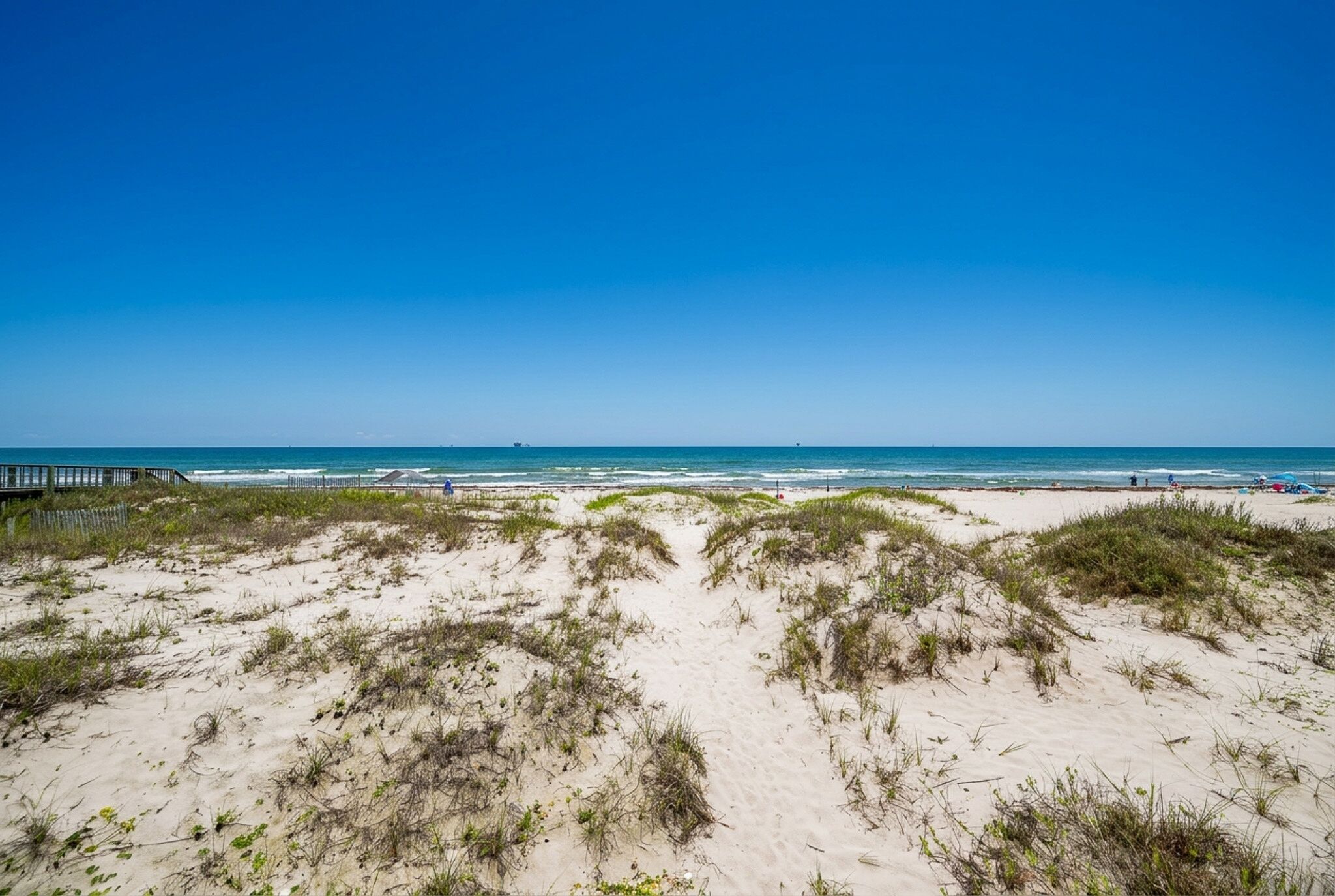 Ein Strand mit Dünen und blauem Himmel.