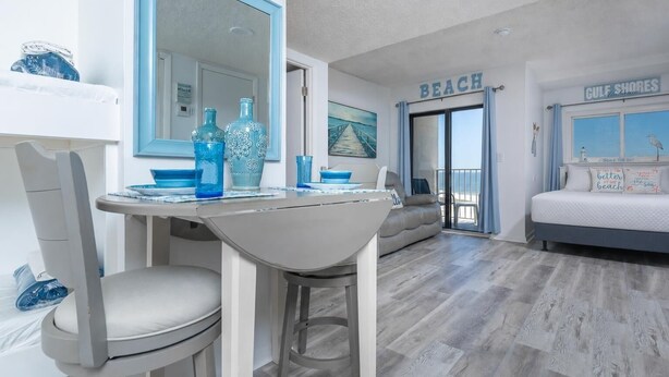 Una sala moderna con comedor, un sofá, una cama y vistas a la playa.