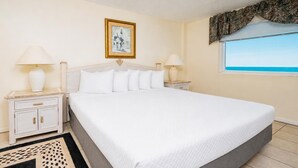 Habitación de hotel con una cama grande, dos mesitas de noche con lámparas, un cuadro enmarcado en la pared y una ventana con vistas.