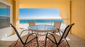 Una mesa redonda con cuatro sillas en un balcón con vista a la playa.