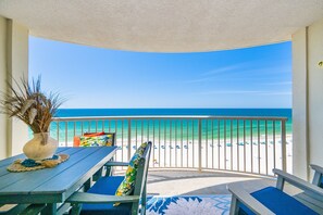 Varanda com vista para a praia, uma mesa com um vaso e cadeiras de praia.