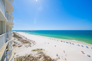 A beach with a pier, white sand, and clear blue water.