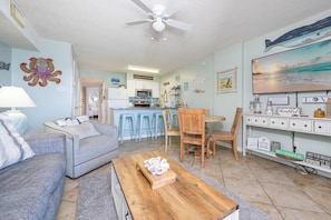 A living room with a sofa, coffee table, and a dining area with chairs and a table.