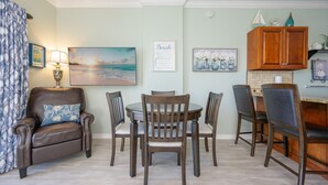 A dining area with a table and chairs, a lamp, and wall art.