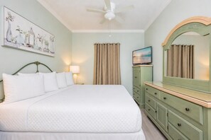 A bedroom with a bed, a ceiling fan, a dresser, a mirror, and a painting on the wall.