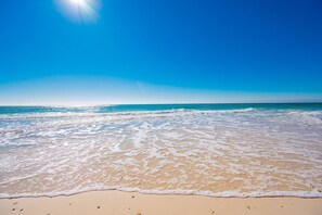 A beach with clear blue water and a sandy shore.