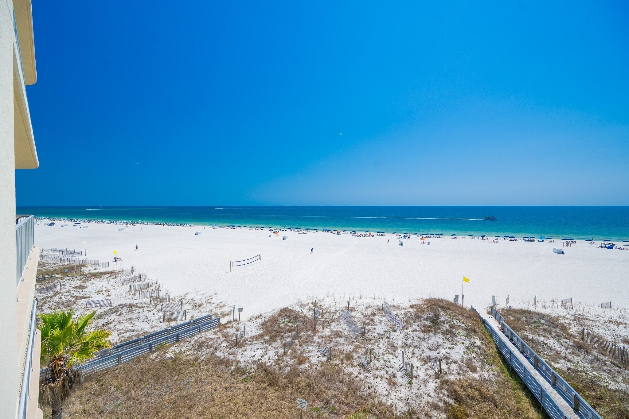 A beach with a clear sky, a sandy shore, and a distant pier.