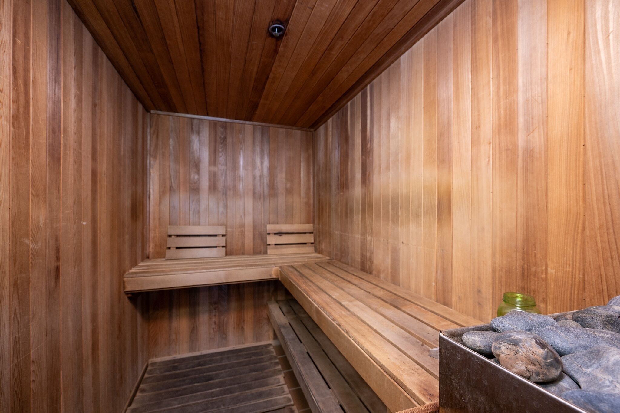Una sauna de madera con bancos y una piedra hundida.