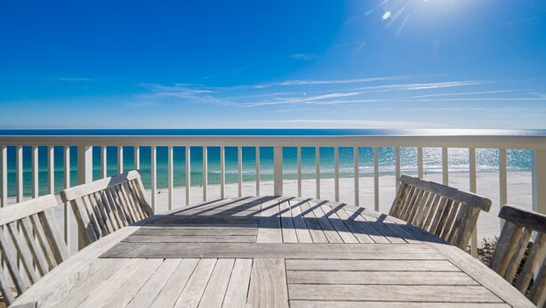 Eine Holzterrasse mit Blick auf den Ozean und den Strand.