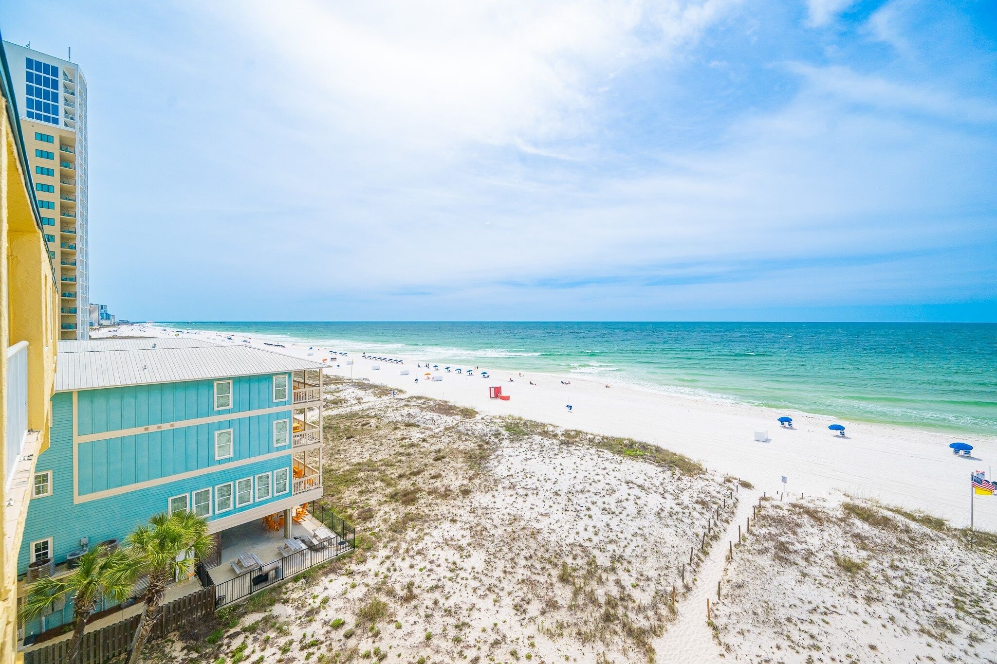A beach view with a building, sandy beach, and ocean.
