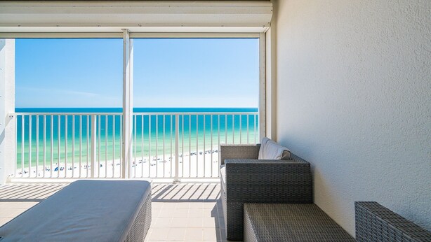 Ein Balkon mit Blick auf den Strand, Korbmöbel und einer weißen Wand.