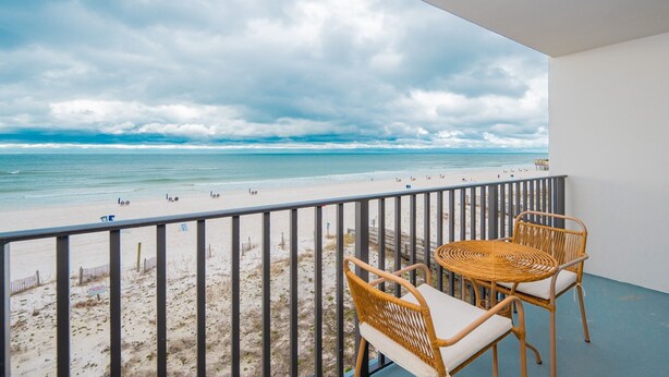 A balcony with wicker furniture overlooking a beach. - Island Sunrise 365 2 Bedroom Condo (Gulf Shores)