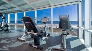 A gym with exercise equipment and large windows overlooking a beach. - Island Tower 601 3 Bedroom Condo (Gulf Shores)