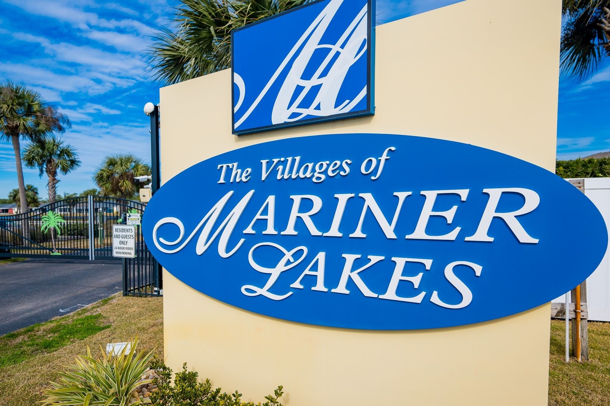 A sign for "The Villages of Mariner Lakes" with a Coca-Cola logo above it.