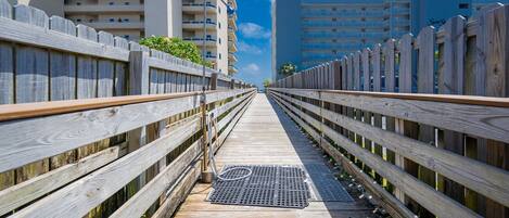 A wooden boardwalk leading to a high-rise building with multiple balconies.
