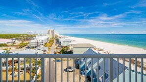 A coastal hotel with a beach view, multiple buildings, and a clear sky.