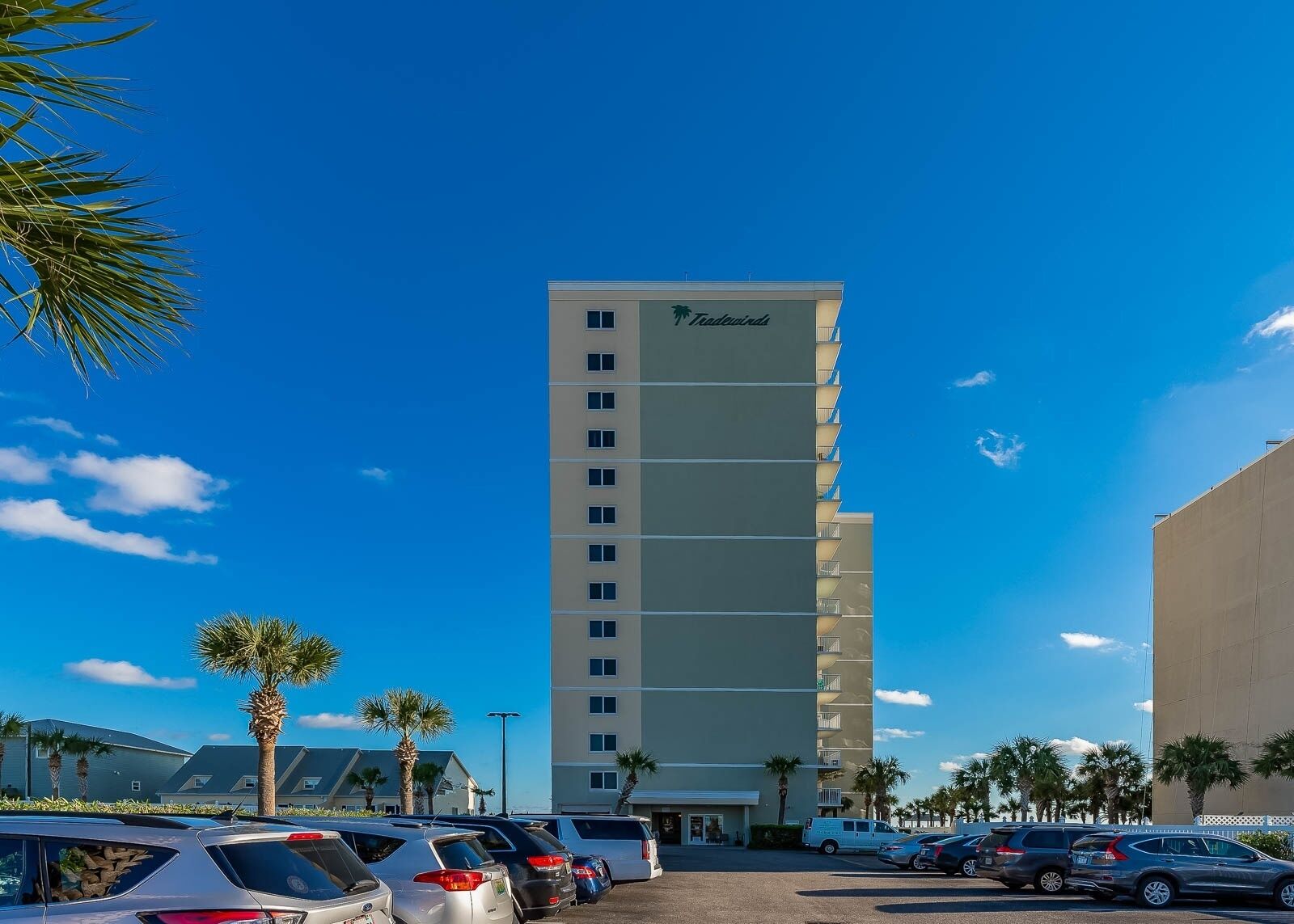 A tall hotel building with a modern design, featuring a prominent logo at the top.