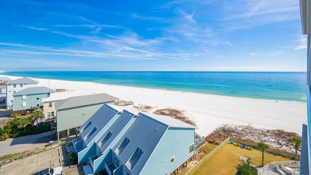 A beachfront property with a clear view of the ocean and sandy beach.