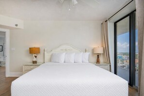 A hotel room with a large bed, two bedside tables with lamps, a view of the city through a balcony. - Bluewater 801 3 Bedroom Condo (Orange Beach)