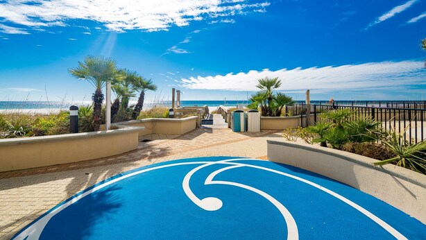 Un sentier menant à une plage bordée de palmiers et dotée d’une piste cyclable bleue.