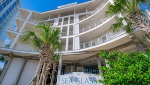 A multi-story hotel with balconies, palm trees, and a sign reading 'SEA GLASS.'