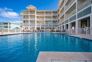 Ein Hotel mit Schwimmbad, mehreren Balkonen und blauem Himmel.