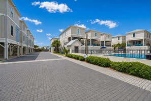 A residential area with a paved walkway, a swimming pool, and houses with balconies. - West Side Cottages U 3 Bedroom Home (Gulf Shores)