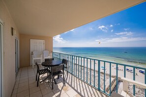 A balcony with a view of the beach, a door, and a table with chairs. - Surfside Shores 1804 2 Bedroom Condo (Gulf Shores)