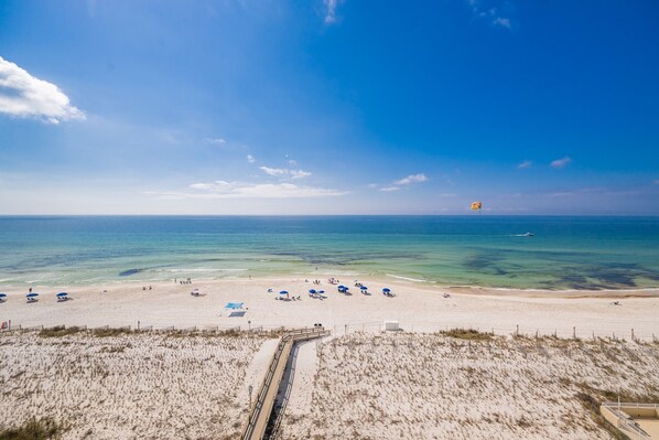 A beach with a clear sky, a sandy shore, and a jet ski in the distance.