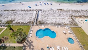 Un complexe hôtelier doté d’une piscine, d’une plage et d’un espace clos avec des chaises longues.