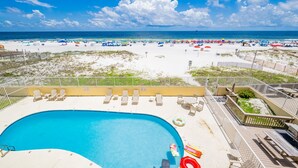 Ein Poolbereich mit Liegestühlen und Blick auf den Strand.