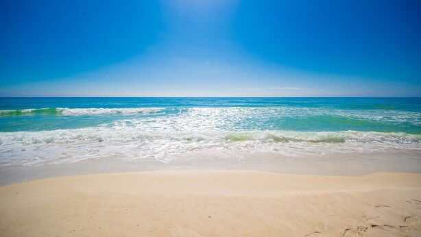 Ein Strand mit klarem, blauem Wasser und sandigem Ufer.