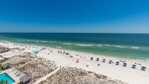 A beach with sun loungers and umbrellas, a pool, and a clear view of the ocean. - Seacrest 805 1 Bedroom Condo (Gulf Shores)