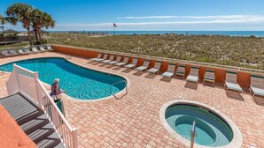 A pool area with a view of the ocean, lounge chairs, and a flag. - Seacrest 805 1 Bedroom Condo (Gulf Shores)