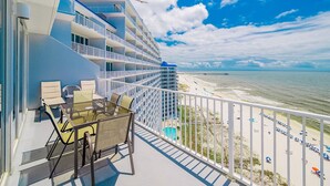 A balcony with a view of the beach, a pier, and a cruise ship in the background. - Lighthouse 1417 1 Bedroom Condo (Gulf Shores)
