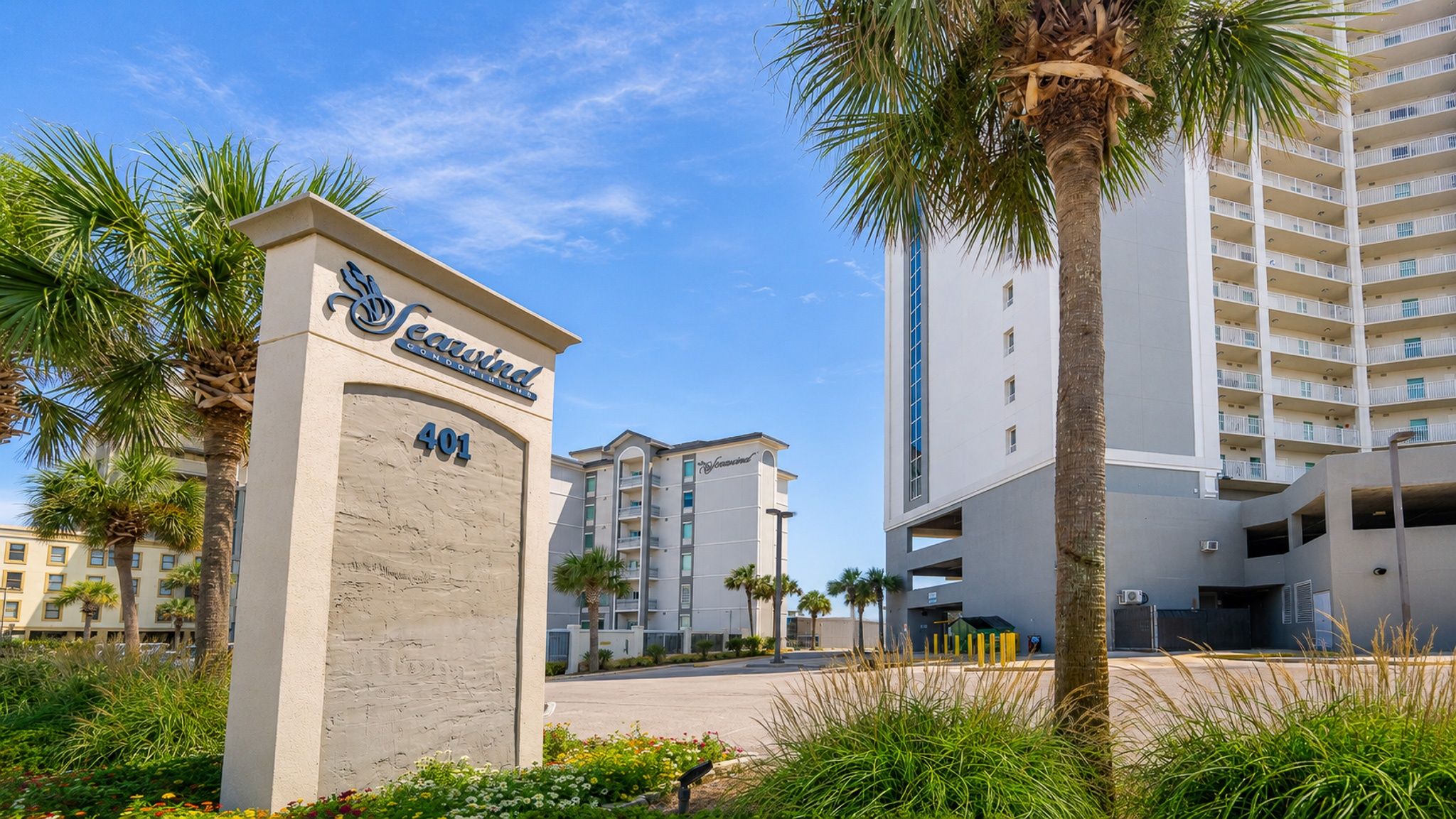 A Seavind condominium building with a modern design, numbered 401, surrounded by palm trees and other greenery.