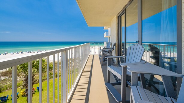A balcony with a view of the beach, white chairs, and a glass railing. - Seaside Beach & Racquet 4407 3 Bedroom Condo (Orange Beach)