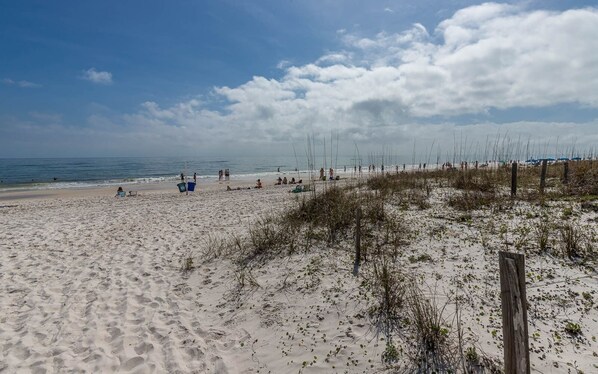 A sandy beach with sparse vegetation and a wooden fence. - Gulf Side Townhomes 20 2 Bedroom Condo (Gulf Shores)