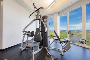 Une salle de sport équipée de matériel d’exercice, dotée de grandes fenêtres et offrant une vue sur l’extérieur.