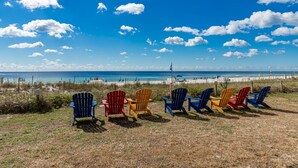 A beach with a row of colorful Adirondack chairs facing the ocean. - Seaside Beach & Racquet 5916 2 Bedroom Condo (Orange Beach)