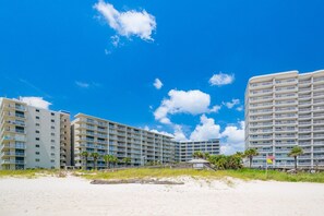 A beachfront hotel with multiple floors, balconies, and a sandy beach in the foreground. - Seaside Beach & Racquet 5916 2 Bedroom Condo (Orange Beach)