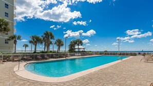 A rectangular swimming pool with a tiled deck, surrounded by palm trees and a white fence. - Seaside Beach & Racquet 5916 2 Bedroom Condo (Orange Beach)