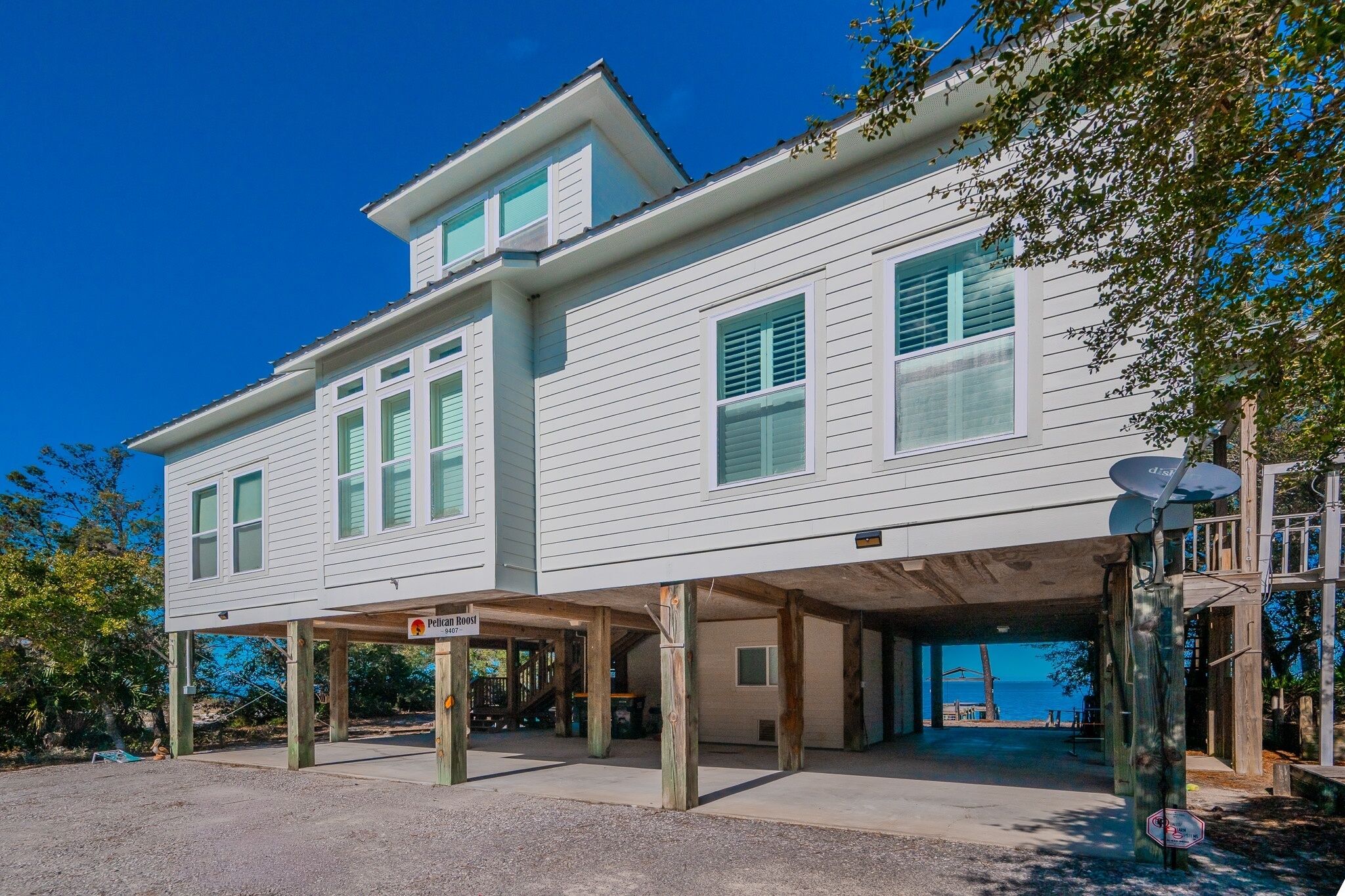 A two-story house with a covered parking area and a view of the ocean.