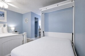 A bedroom with a bed, a nightstand, a wall clock, and a ceiling fan. - Sugar Beach 353 1 Bedroom Condo (Gulf Shores)