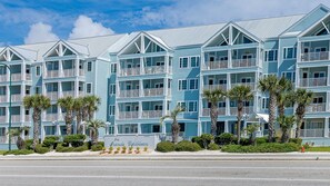 Un hotel de varios pisos con balcones, palmeras y un cartel que dice "Grande Cayman".