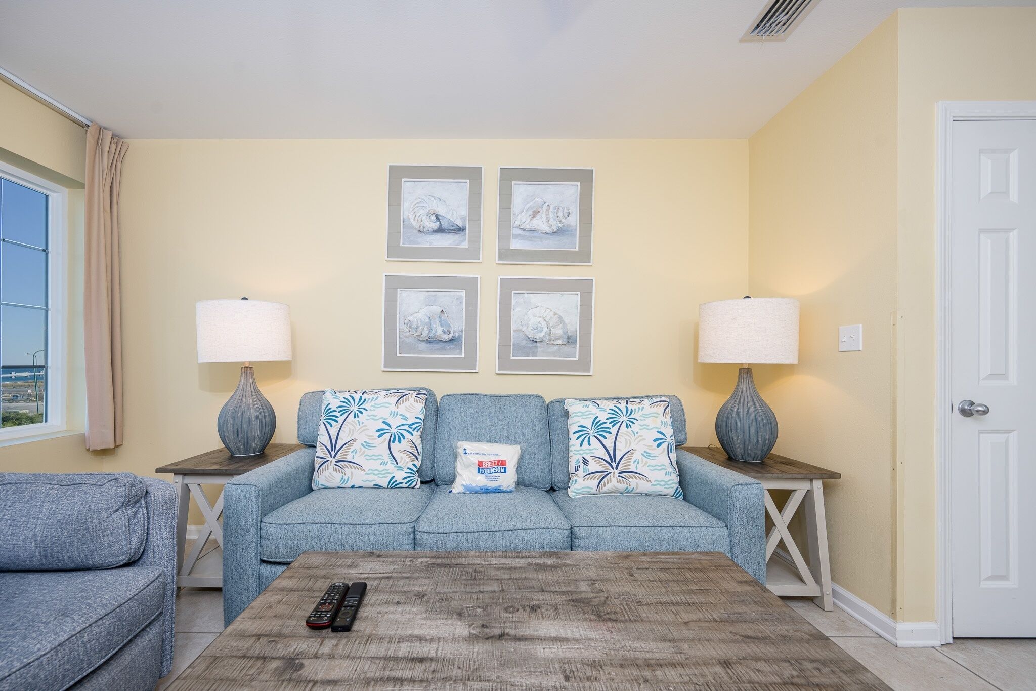 A living room with a sofa set, two side tables with lamps, a coffee table, and four framed pictures on the wall.