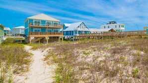 A beachfront property with multiple houses, a wooden boardwalk, and a sandy path. - Funspot 1713 5 Bedroom Home (Gulf Shores)