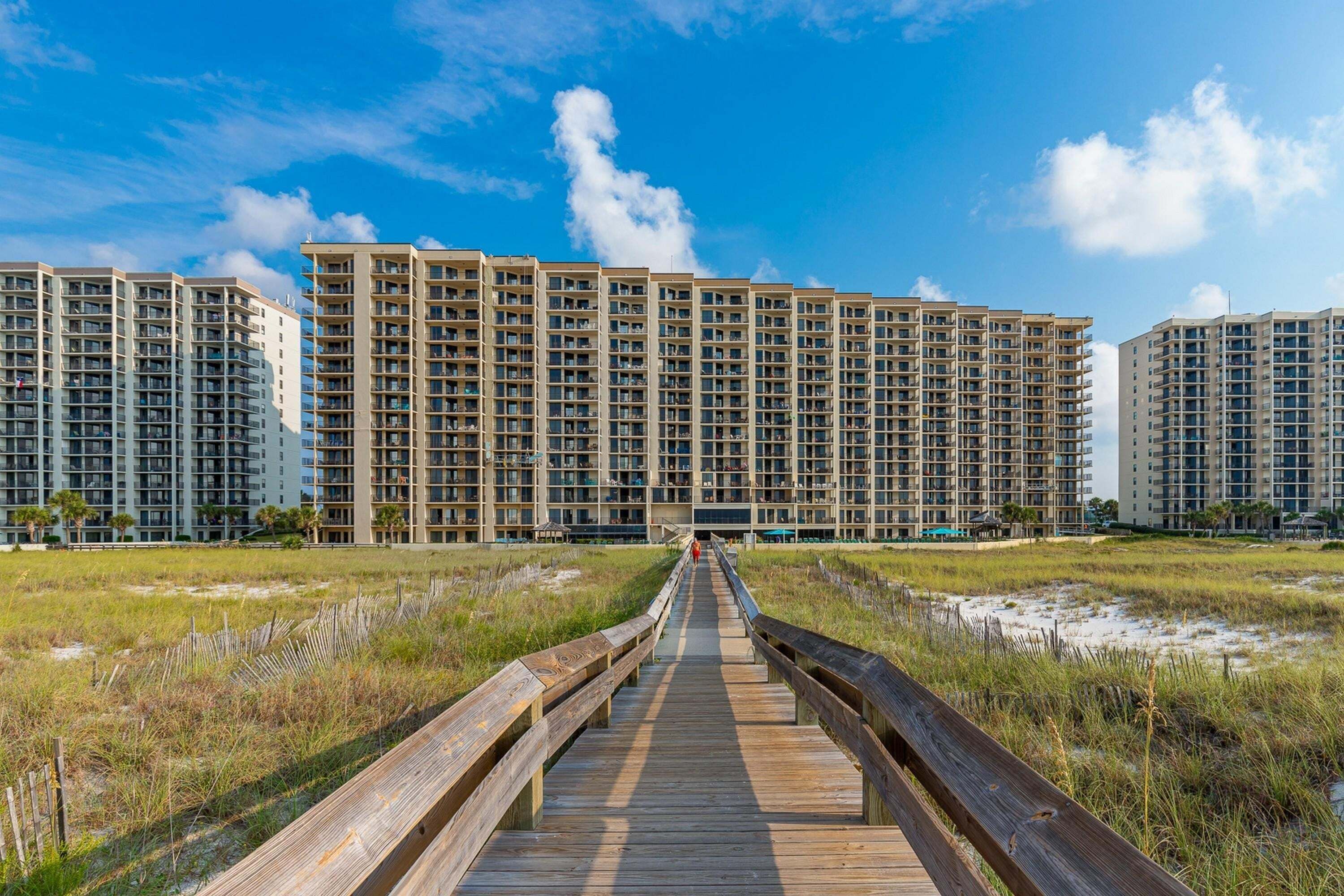 A boardwalk leading to high-rise residential buildings with multiple balconies.